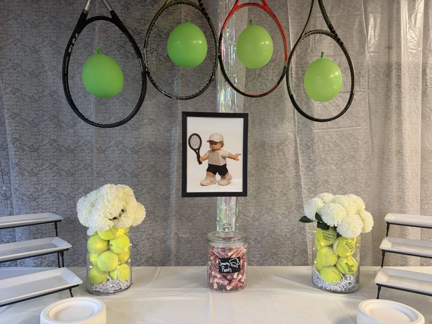 Tennis-themed decor with balloons and flowers.