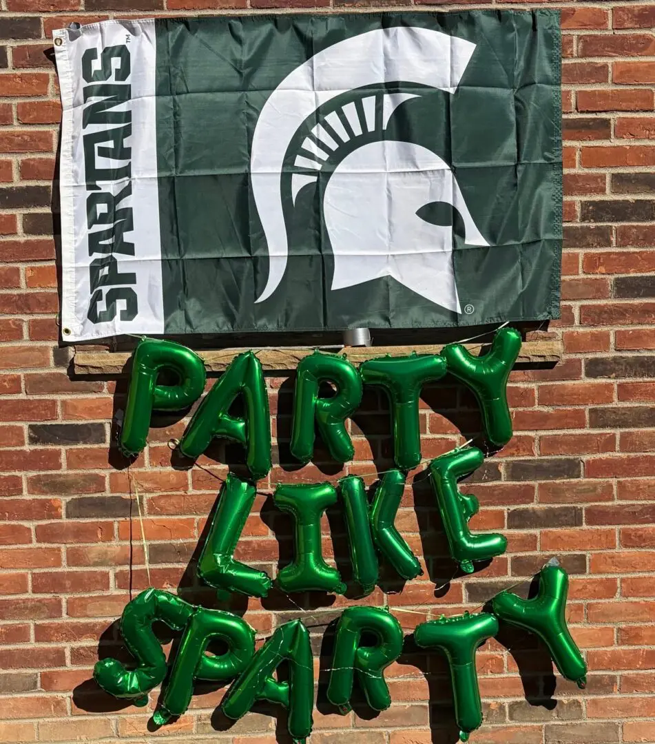 Green balloon letters spelling "PARTY LIKE SPARTY" on wall.