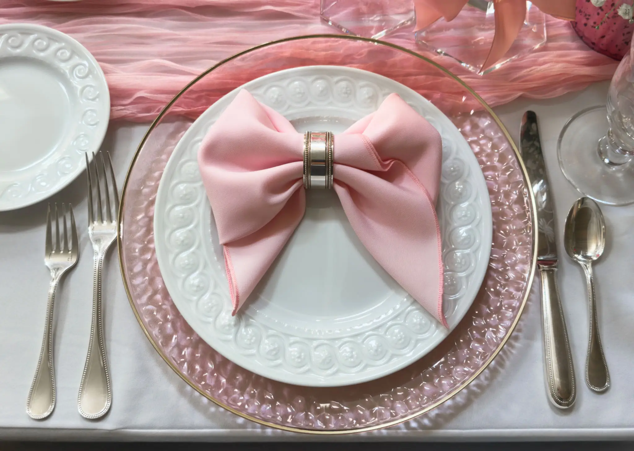 Elegant table setting with pink bow and plates.