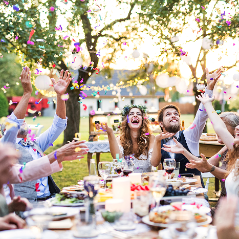 People celebrating outdoors with confetti and laughter.